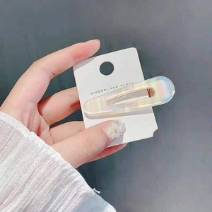 Detailed view of rectangular holographic hair clip with iridescent finish on a white card