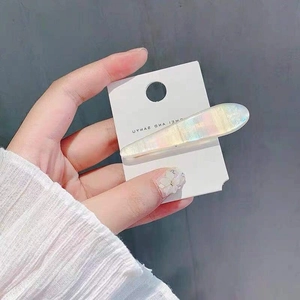 Detailed macro view of an iridescent shell-effect hair clip on a white display card