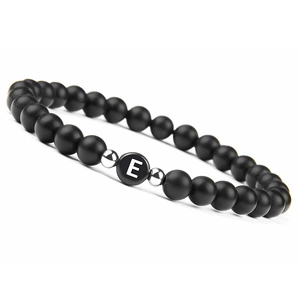 Detailed macro view of 6mm matte black onyx beads with a silver charm letter E on the bracelet