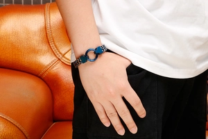 Close-up of men's blue metal ring buckle and silver-black textured link chain bracelet