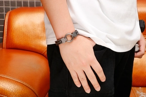 Detail of gunmetal stainless steel braided chain bracelet with a round spring clasp on wrist
