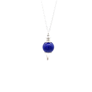 Close-up of blue gemstone ball pendant with silver metal tip and fine cross chain