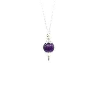 Macro detail of natural purple amethyst crystal ball pendant on a silver link chain