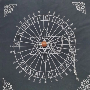 Macro shot of stone pendulum with silver chain on black English divination chart cloth