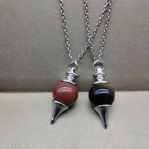 Detailed view of silver pendulum necklaces with tiger eye and red jasper gemstones