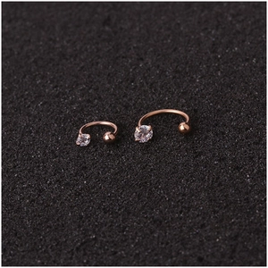 Rose gold horseshoe nose studs with cubic zirconia and steel ball ends on a dark surface