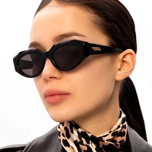 Detail of black irregular cat-eye sunglasses featuring golden metallic temple accents