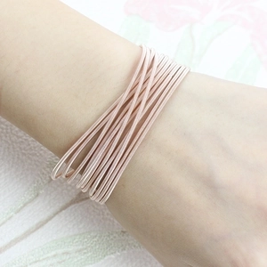 Rose gold multi-coil spring bracelet in carbon steel worn on a female wrist