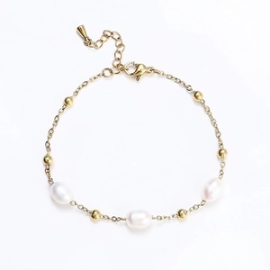 Macro detail of waterproof gold beaded bracelet with three elegant white oval pearls