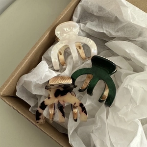 Three acetate shark hair clips in cream, tortoiseshell and green in a gift box