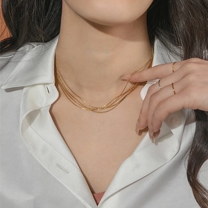 Elegant multi-layered gold silk titanium necklace set on model with silk shirt