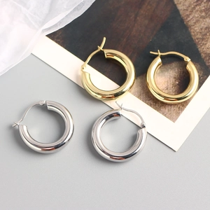 Flat lay of classic thick gold and silver hoop earrings on artistic background paper
