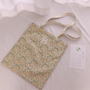 Close-up of yellow floral cotton tote bag with minimalist woven label and canvas handles