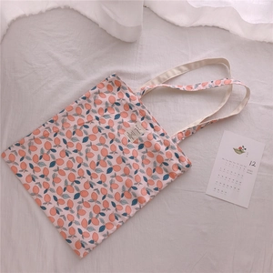 Detailed view of large floral cotton tote bag with orange lemon print and fabric label
