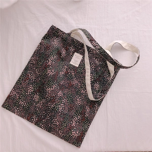Detail of floral canvas tote bag showing the dark flower pattern and cream strap