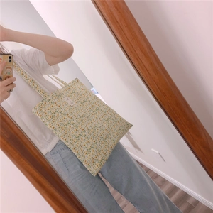 Detail view of floral cotton tote bag featuring green patterns and white label