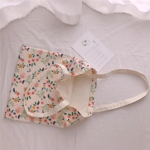 Detailed macro view of the colorful floral pattern on a cream cotton canvas shoulder bag