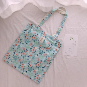 Close-up of floral cotton tote bag with delicate animal patterns label and soft texture