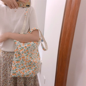 Detail view of floral cotton tote bag with orange print and white woven label