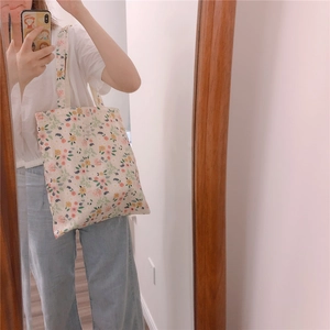 Detail of floral canvas tote bag with small flower pattern and woven brand label