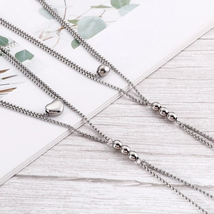 Minimalist double-layered silver necklace with round beads and heart pendant on wood