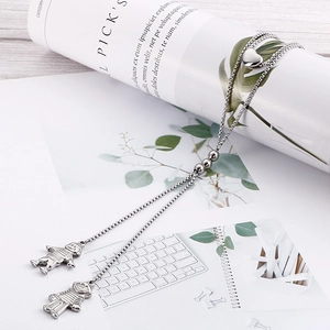 Minimalist double layer silver necklace with boy and girl pendants on a desk background