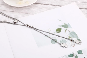 Detail of silver double-layered necklace with heart and figure pendants on a wooden table