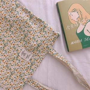 Detail of floral cotton tote bag with yellow blossoms and artistic textile label
