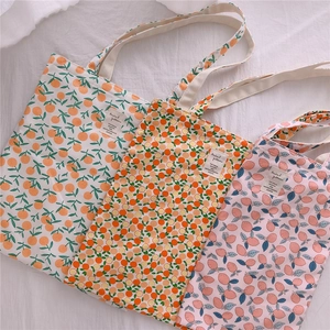 Detailed view of three floral cotton tote bags with fruit patterns on linen background