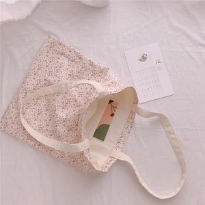 Detail view of floral cotton tote bag with pink flower pattern on a soft fabric background