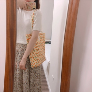 Detailed mirror selfie of cream cotton tote bag with vibrant orange fruit pattern print