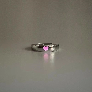 Detail of silver adjustable open ring featuring a glowing pink heart-shaped center