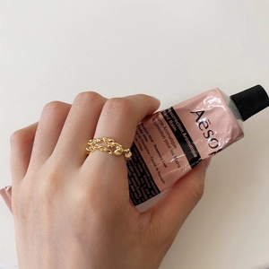 Detailed view of irregular gold chain ring worn on hand with minimalist aesthetic
