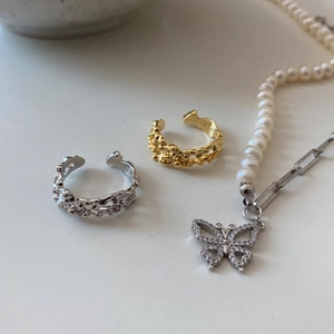 Close-up of S925 sterling silver stamp on golden lava ring and pearl butterfly necklace