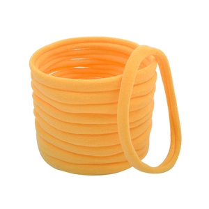 Macro detail of seamless bright orange elastic hair ties showing knit fabric texture