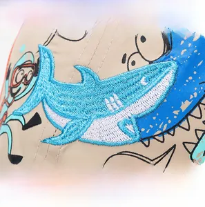 Detailed close-up of blue shark embroidery and cartoon prints on khaki twill kids cap