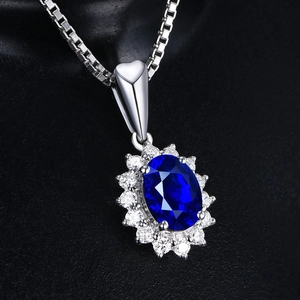 Macro detail of oval blue sapphire pendant with diamond halo and silver heart clasp