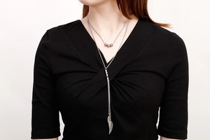 Dettaglio di collana argento a due strati con pendenti a piuma e perline su una modella