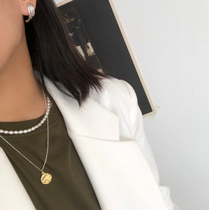 Detail of layered freshwater pearl necklace with gold coin pendant on a stylish model