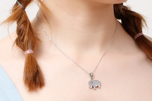 Detail view of a silver elephant pendant necklace worn by a model in a bright setting