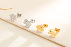 Close-up of cute elephant stud earrings in gold and silver finish on a beige envelope