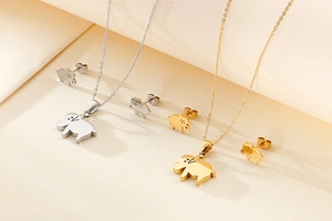 Detailed view of silver and gold stainless steel elephant necklaces and stud earring sets