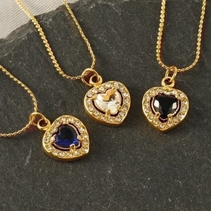 Gold heart-shaped zircon necklaces in blue, clear and black on a dark slate background