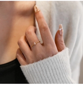 Detail of a twisted gold ring with a pink oval gemstone worn on a model's hand