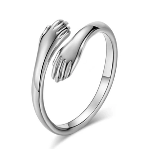 Detailed view of silver hugging hands open ring with high-polish metallic finish