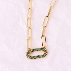 Close-up of gold paperclip chain necklace with green pave-set zircon oval link