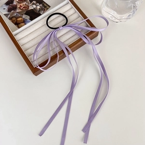 Close-up of elegant purple ribbon bow hair tie with long streamers on a white display