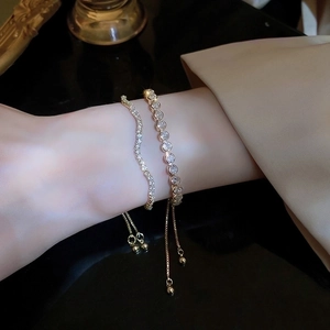 Detailed view of adjustable gold-finish wavy diamond bracelets on a wrist