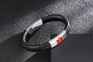 Macro detail of medical alert symbol on a black braided leather bracelet with magnetic clasp