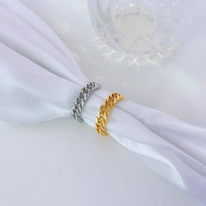 Minimalist 18k gold and silver Cuban chain rings displayed on white silk fabric
